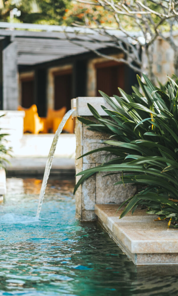 Turquoise water pool exterior in tropics with green vegetation.
